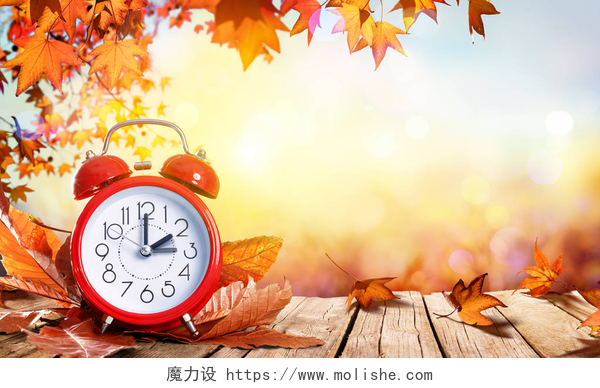 秋天的枫叶和闹钟海报背景日光节约时间概念 — — 时钟和木制的桌子上的叶子